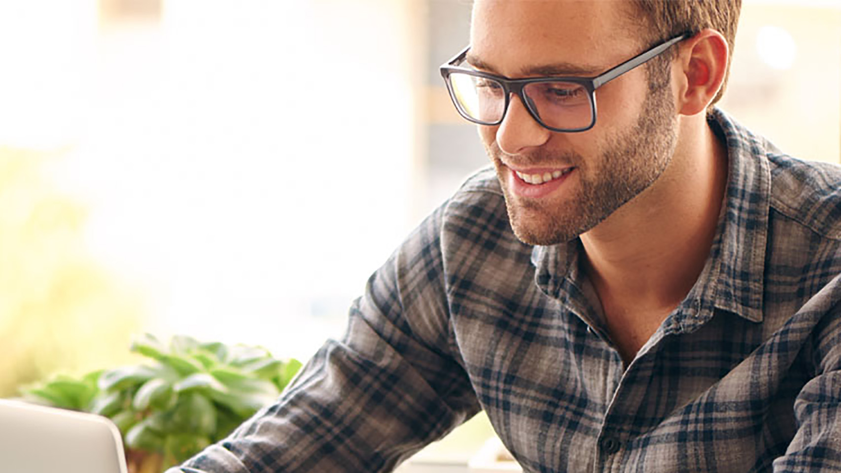 Man smiling while look at and working on a laptop computer